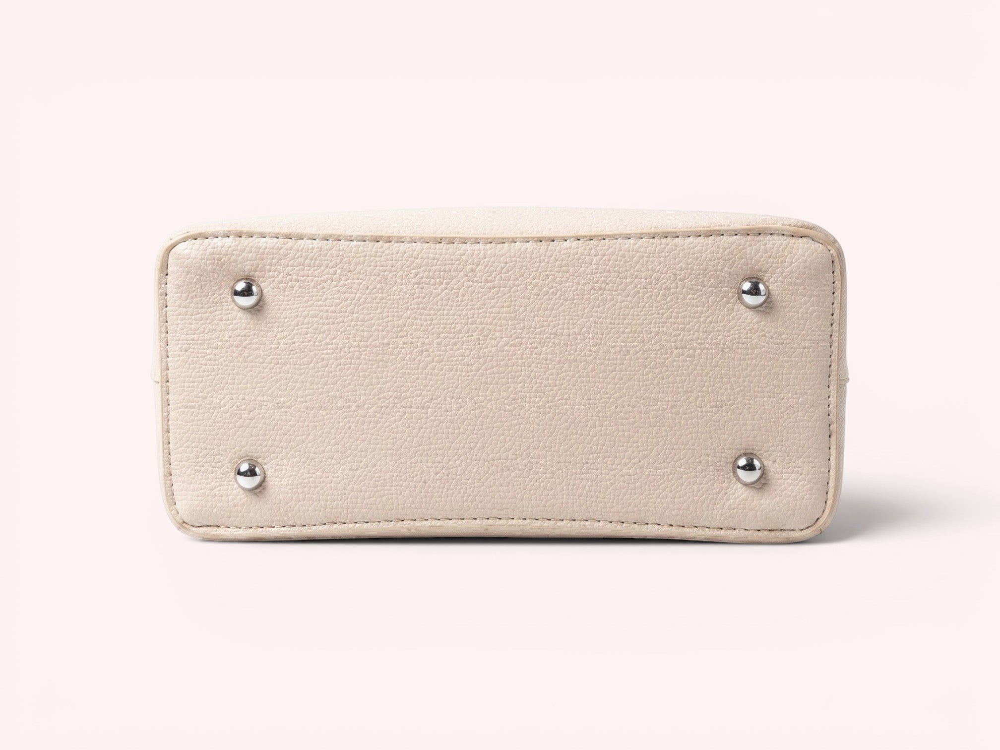 Sheonn beige textured faux leather handbag base with four protective silver-tone metal feet on a white background.