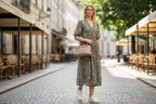 Sheonn tan structured top handle handbag with silver hardware worn by a woman in a floral dress on a city street.
