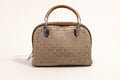 Sheonn structured tan handbag with a patterned exterior, top handle, and polished silver-tone hardware.