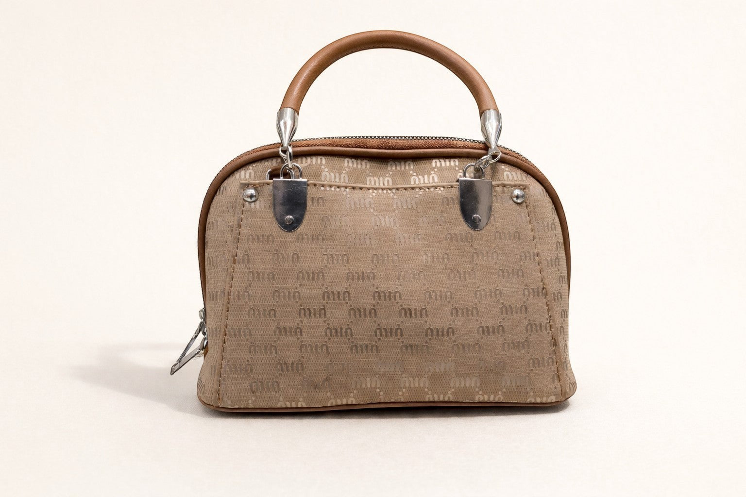 Sheonn structured tan handbag with a patterned exterior, top handle, and polished silver-tone hardware.