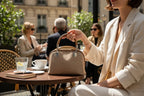 Sheonn structured tan handbag with patterned fabric, silver hardware, and top handle held by a woman at a cafe.